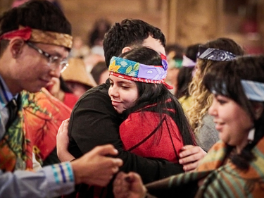 Students participating in a cultural gathering, with individuals embracing in a crowd.